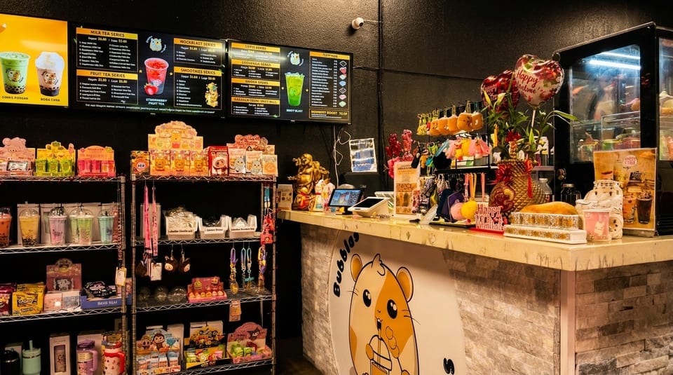 A boba tea shop interior with a counter, menu screens, and shelves displaying drinks and merchandise.