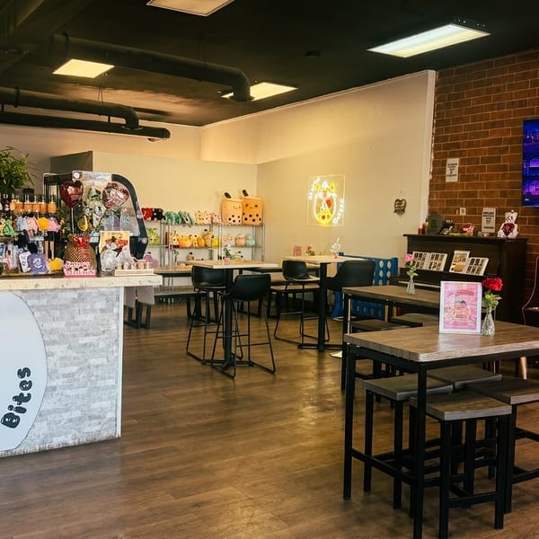 Interior of Bubbles N' Bites, a boba tea shop with tables, counter, and arcade games.