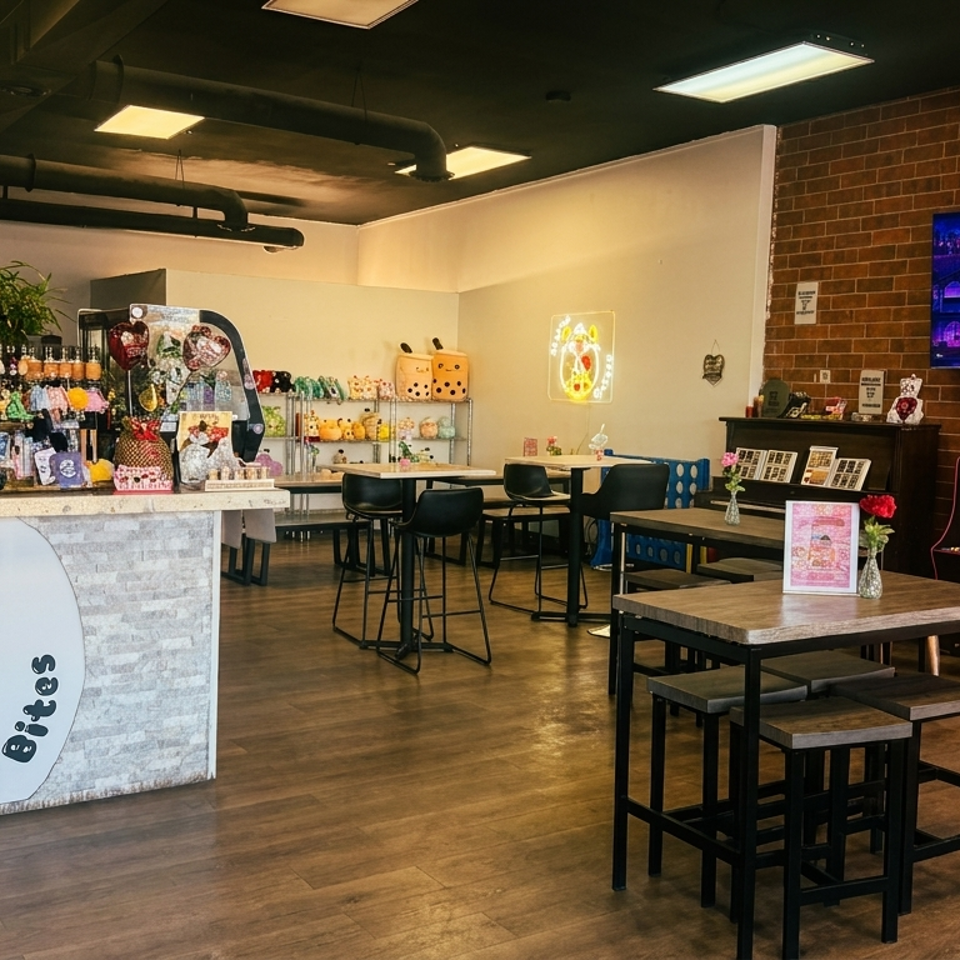 Interior of Bubbles N' Bites, a boba tea shop with tables, counter, and arcade games.