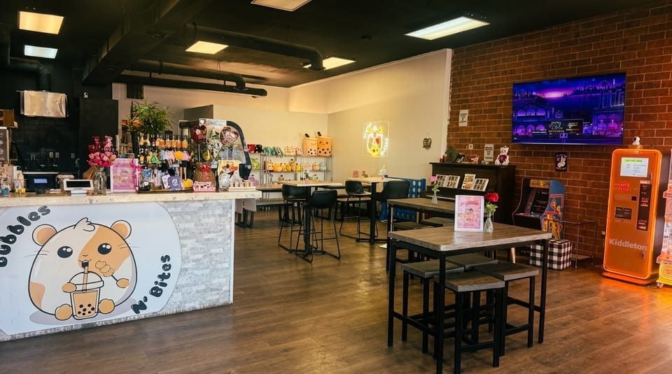 Interior of Bubbles N' Bites, a boba tea shop with tables, counter, and arcade games.